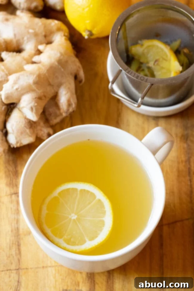Best Lemon Ginger Detox Tea Recipe close up in cup. A comforting mug of lemon ginger tea, garnished with fresh lemon slices and a piece of ginger, ready to be enjoyed.