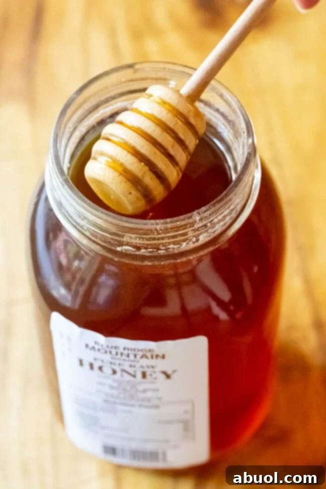 Closeup of honey for lemon ginger tea recipe. Golden, raw honey dripping into a spoon, symbolizing natural sweetness and health benefits.