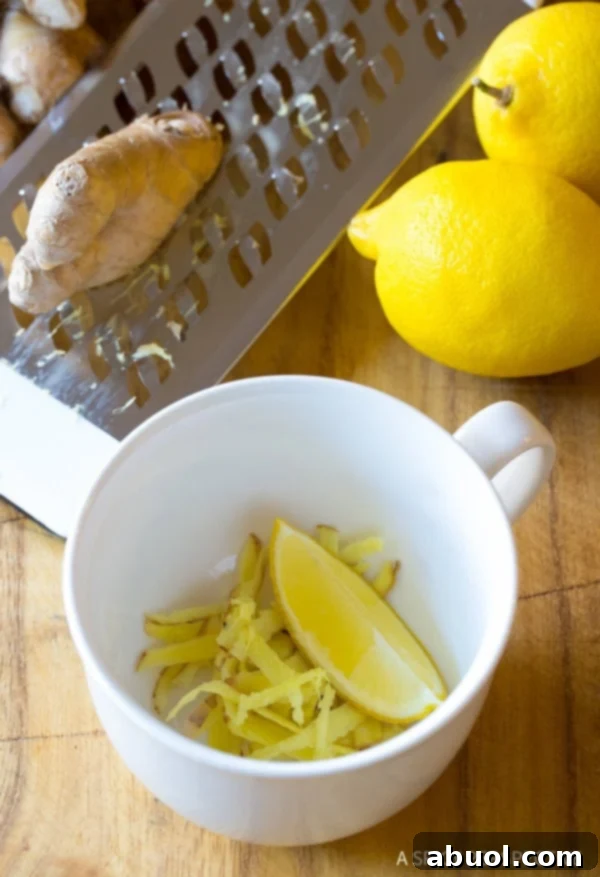 Grated ginger and a lemon wedge in a mug. A ceramic mug with finely grated ginger at the bottom and a fresh lemon wedge resting on the side.