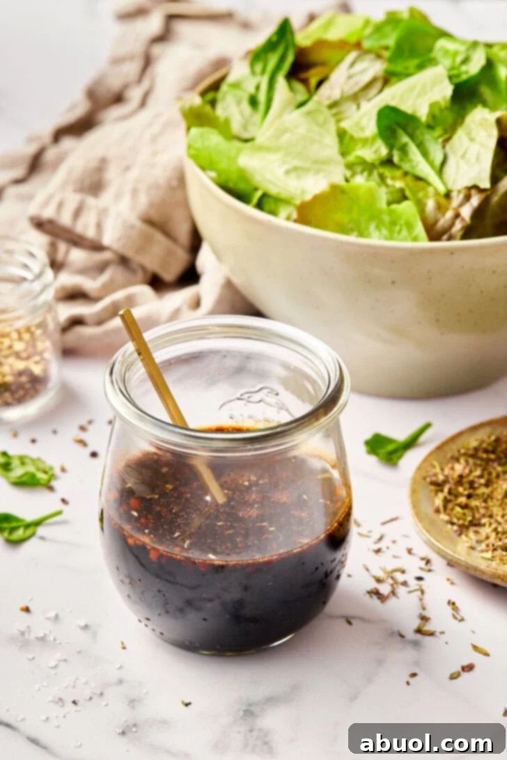 Balsamic vinaigrette in a jar with a salad in the background. 