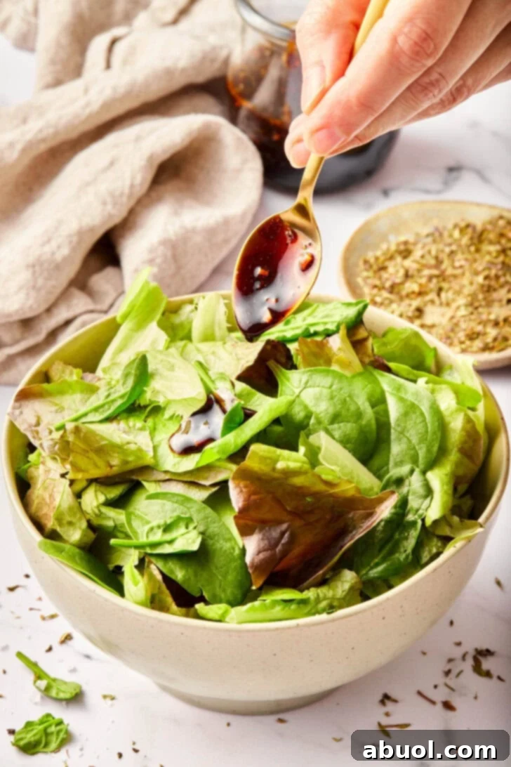 Homemade salad dressing with balsamic vinegar poured over greens.