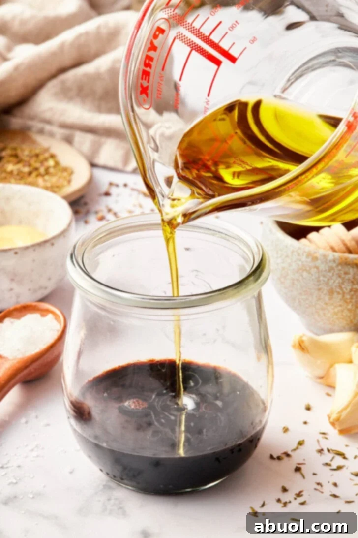balsamic vinaigrette recipe in jar with oil being added