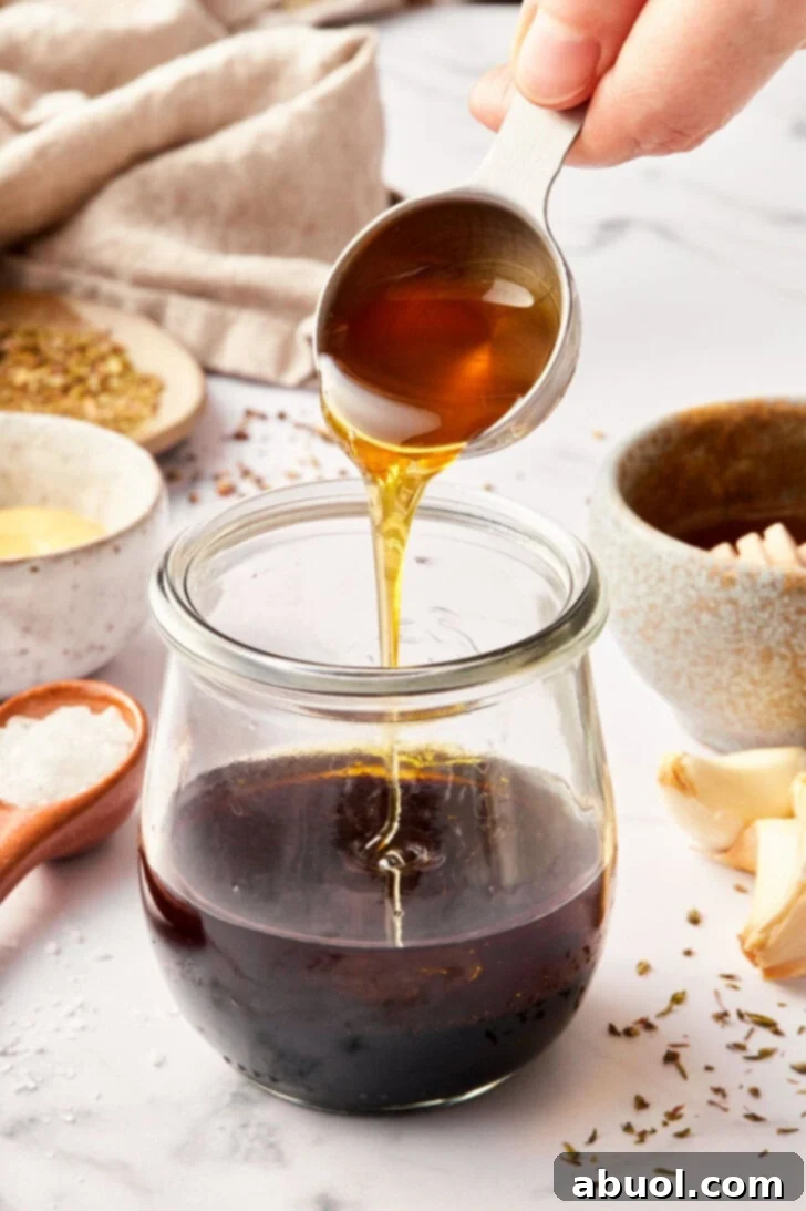 balsamic vinaigrette recipe in jar with honey being added