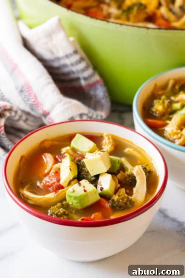 Healthy Southwest Chicken Soup for Detox & Cleanse Two vibrant bowls of Southwest chicken detox soup, garnished with creamy diced avocado, ready for serving.