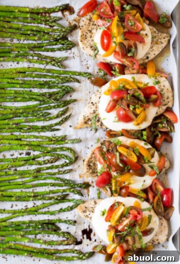Close-up of bruschetta chicken and roasted asparagus on a sheet pan, ready to be served.