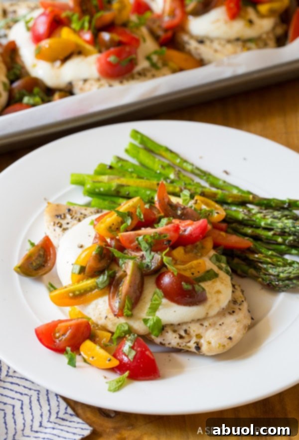 Perfectly cooked cheesy bruschetta chicken with roasted asparagus on a white plate, ready to be enjoyed.