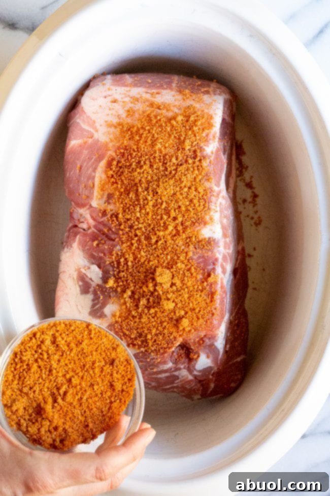 Hand seasoning the pork roast with a spice rub.