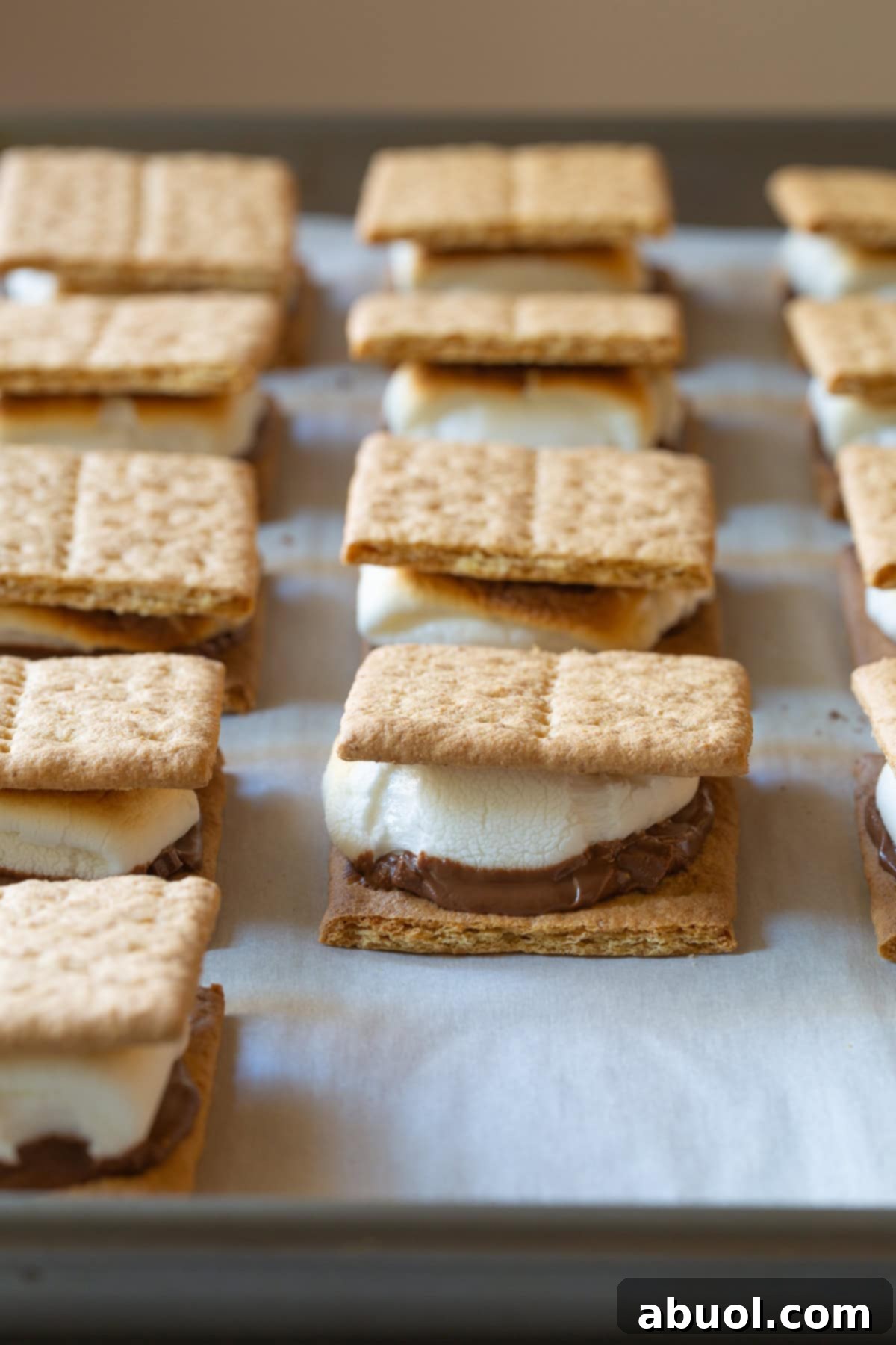 Oven Baked Smores Perfection 4 Baked s'mores lined up perfectly on a baking sheet, ready to be enjoyed.