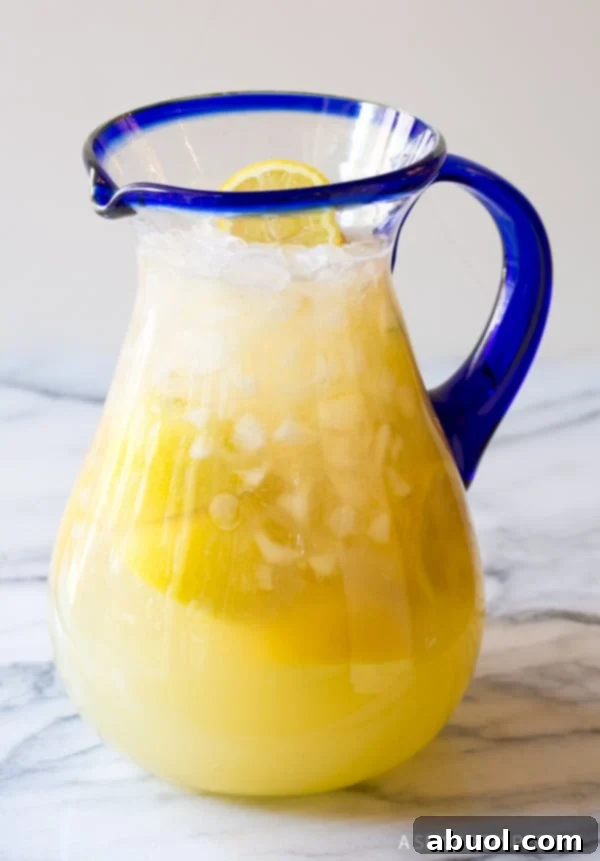 Side view of a pitcher filled with Stevia Lemonade and lemon slices, ready to be served.