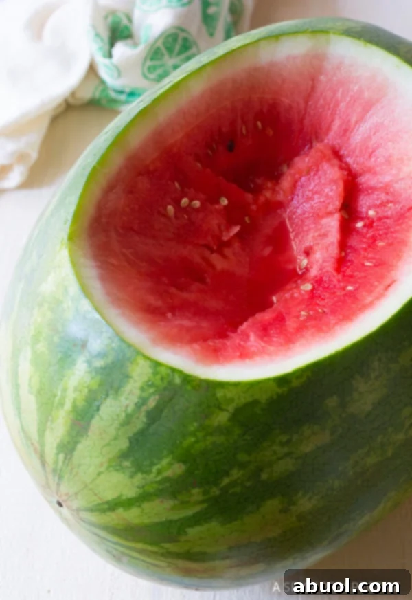 A watermelon with the top cut off and part of the inside scooped out.