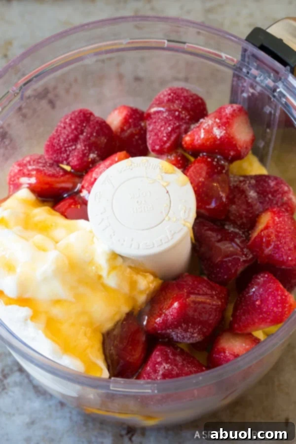 All ingredients for strawberry pineapple sherbet neatly arranged in a food processor bowl, ready for blending.