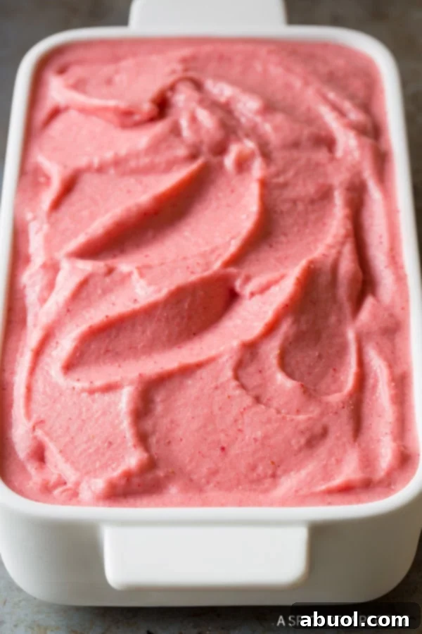 A beautifully presented serving of strawberry pineapple sherbet in a pristine white dish, glistening under soft light.