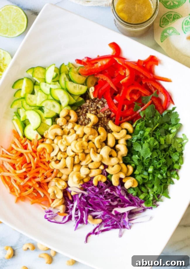 Healthy Thai Quinoa Salad with colorful toppings piled in a bowl, ready to be tossed