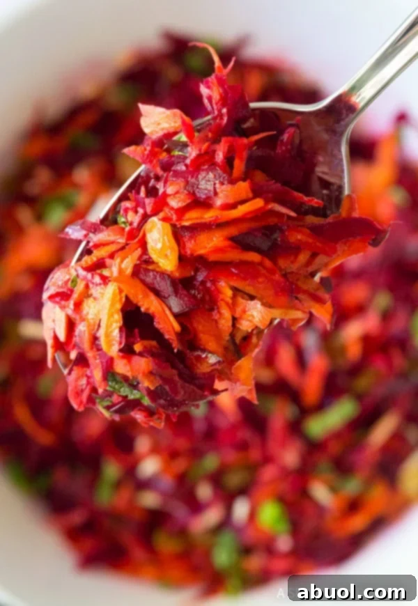 Best Crunchy Beet Carrot Salad spooned up over a bowl, showcasing its texture and ingredients.