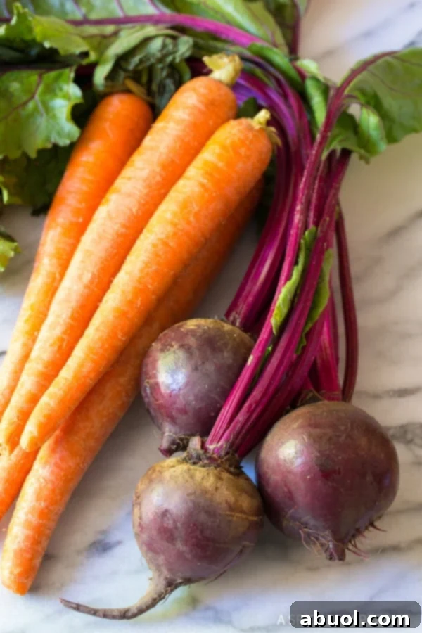 All the fresh ingredients for carrot beet slaw laid out on a cutting board.