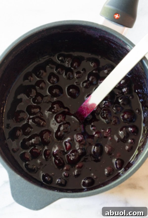 Warm blueberry sauce gently simmering in a saucepan, its vibrant color and luscious texture developing.