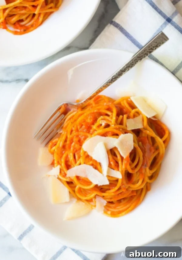Roasted red pepper pasta in a bowl with shaved parmesan cheese on top. 