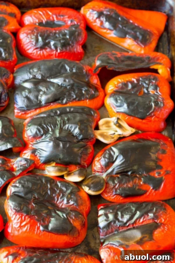 Red bell peppers on a baking sheet after being roasted. 