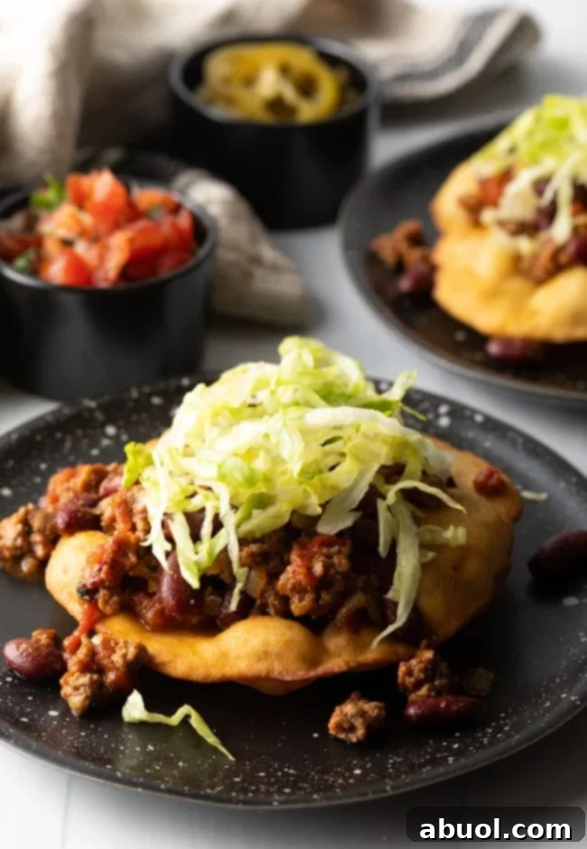 Expert hands assembling a crispy tortilla taco with generous portions of meat and fresh lettuce.