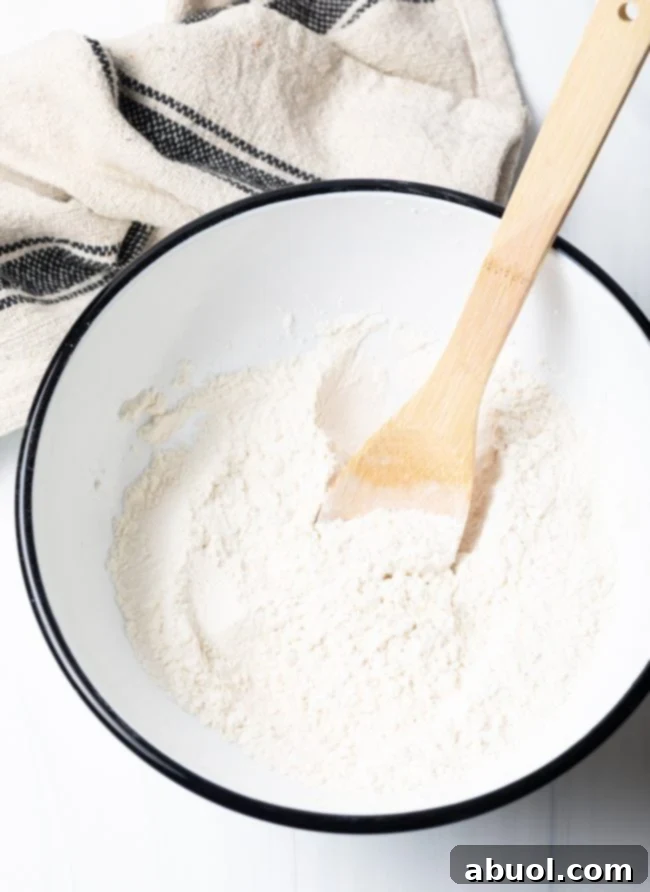 Dry ingredients in a mixing bowl with a wooden spoon, ready for the next step.