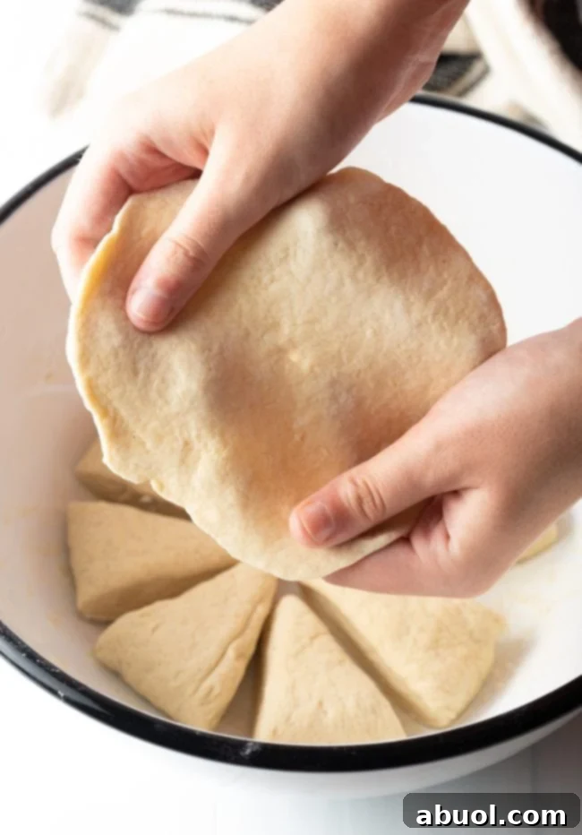 Hands expertly pulling and stretching the easy-to-work-with dough to form perfect tortilla-like shapes.