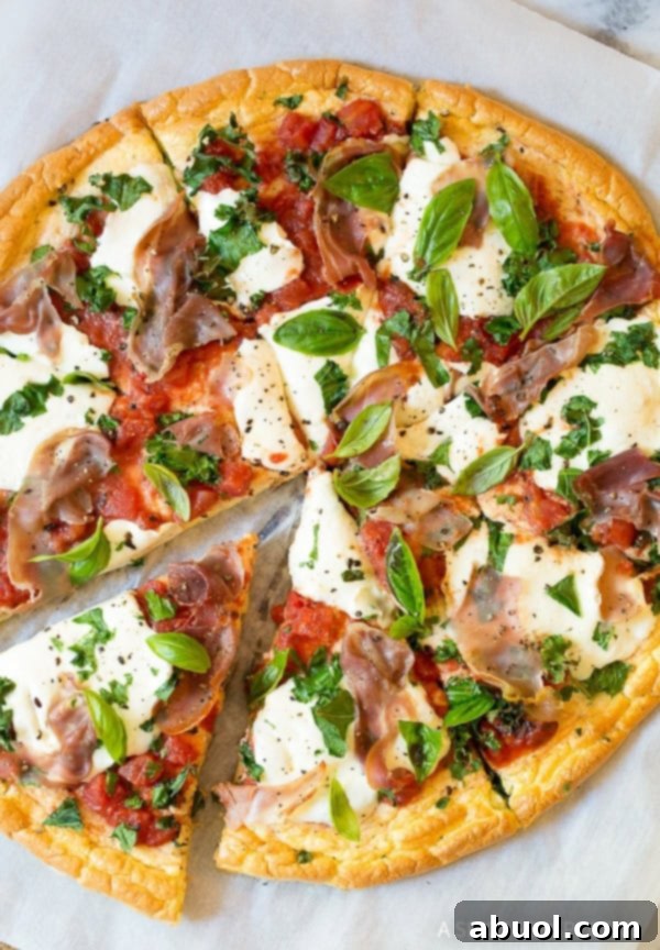 Overhead shot of low carb cloud bread pizza with mozzarella and prosciutto, ready to be sliced.