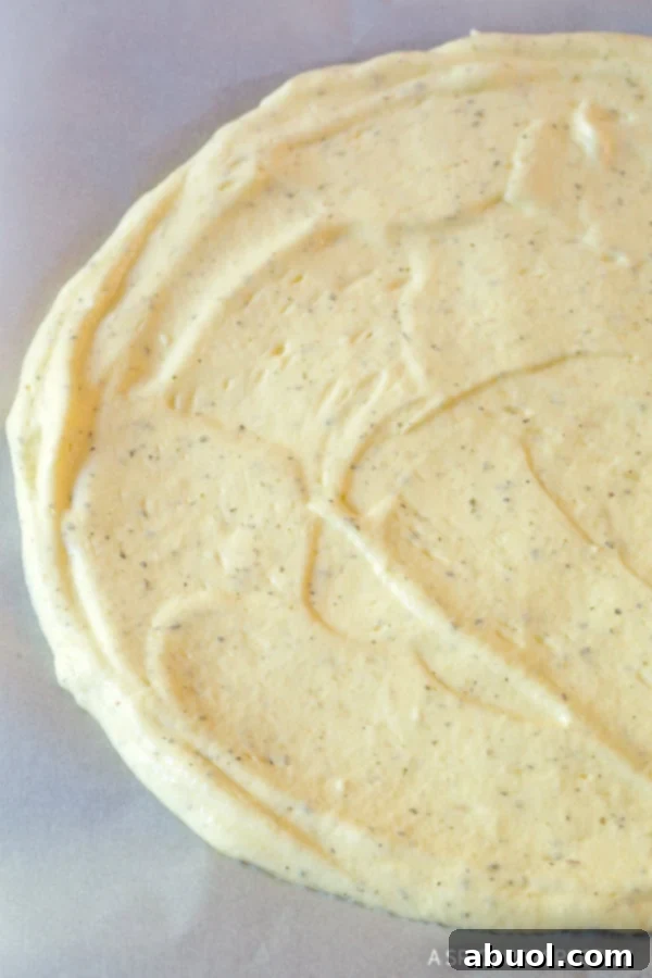 A perfectly circular cloud bread crust, baked to a golden hue, resting on parchment paper on a baking sheet.