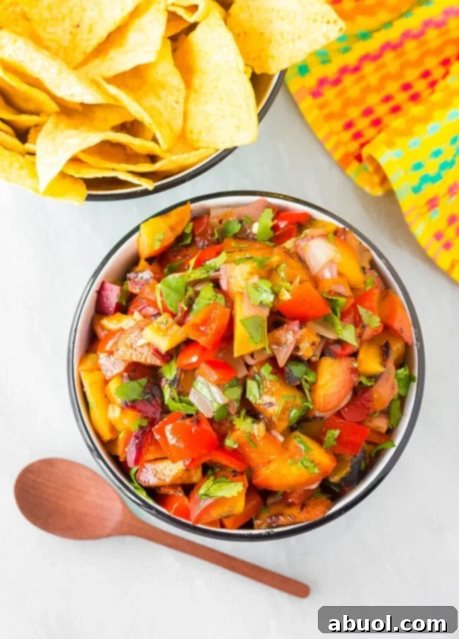 A close-up, top-down view of a vibrant bowl of grilled peach salsa, showcasing its chunky texture and colorful ingredients.