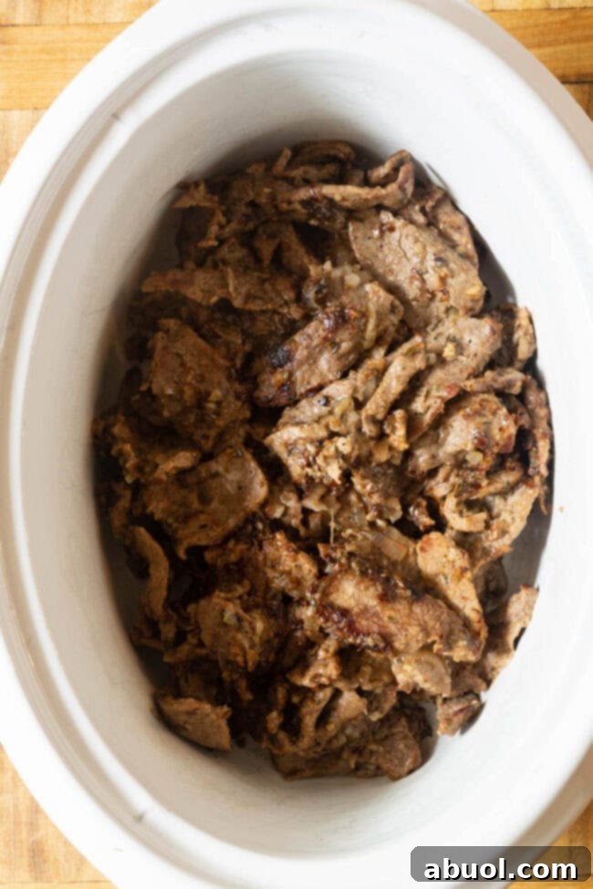 Beef chuck roast prepared for stroganoff, nestled in a slow cooker crock.