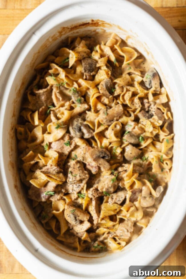 Slow Cooker Beef Stroganoff in the crockpot, with the cooked egg noodles gently mixed in.