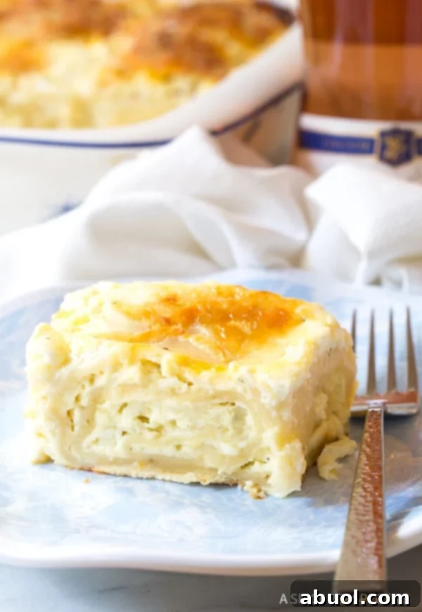 A close-up of a single, perfectly golden-brown piece of Croatian Cheese Strukli, served on a white plate with a fork, revealing its tender, cheese-filled layers.