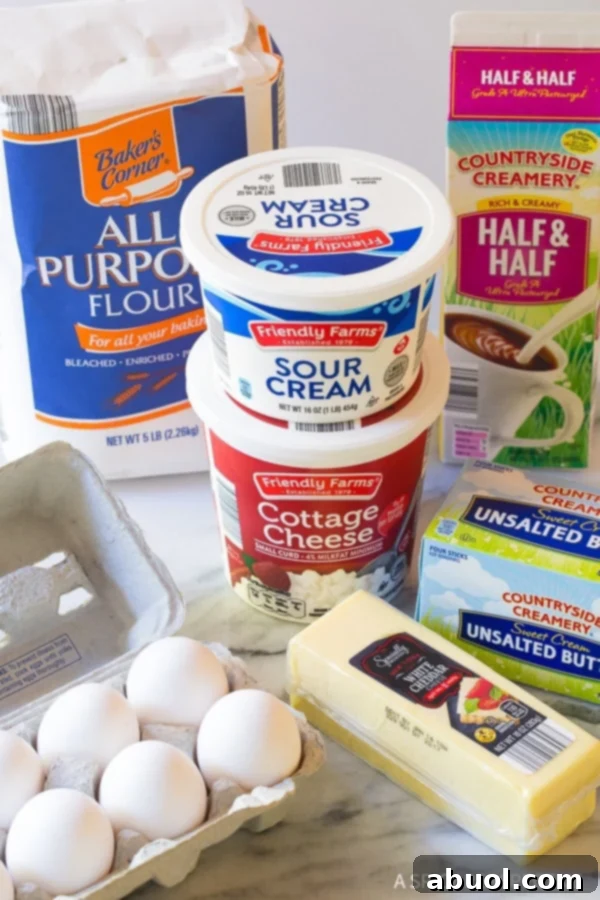 A vibrant display of fresh ingredients for Croatian Cheese Strukli, neatly arranged on a rustic wooden surface, including flour, eggs, butter, cottage cheese, sour cream, shredded white cheddar, and herbs.