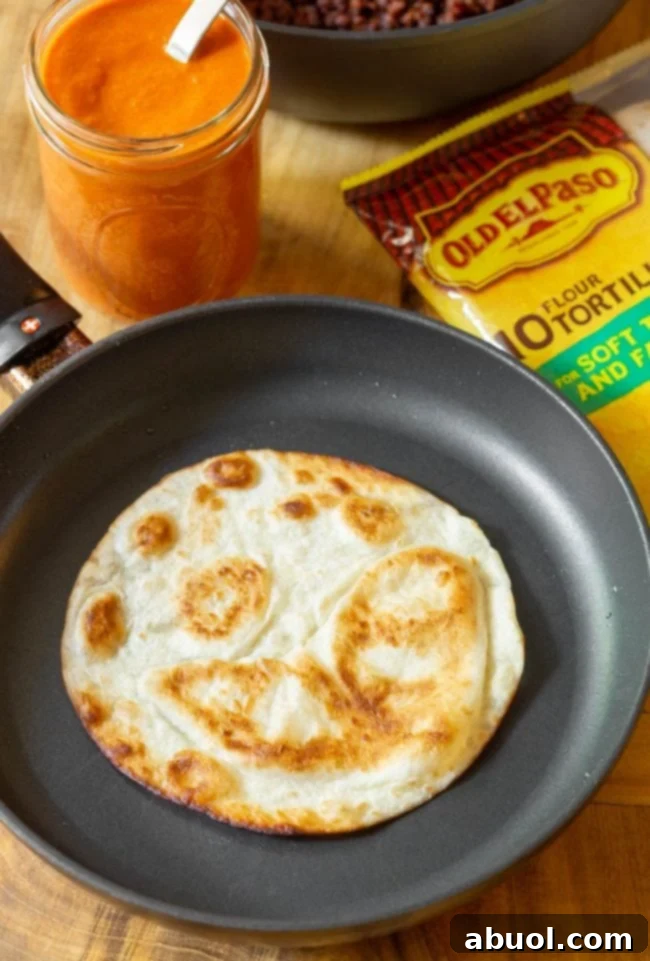 A flour tortilla puffing up and golden in a hot skillet, ready to be flipped.