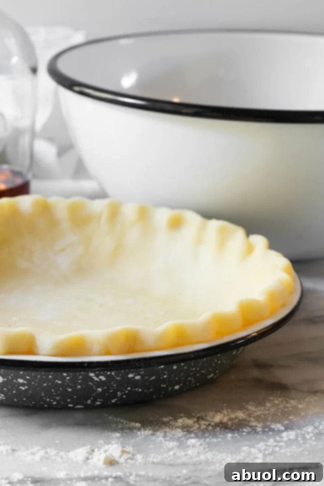 Unbaked pie crust perfectly fitted into a stylish pie pan, with crimped edges, ready for the filling.