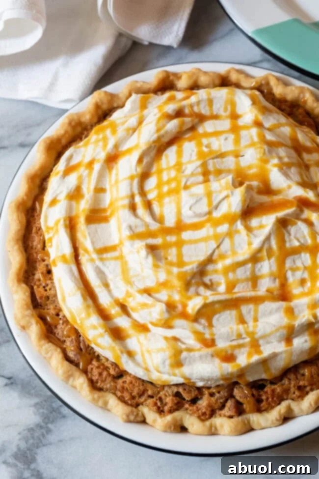 A close-up of Kentucky Derby Pie generously topped with swirls of homemade salted caramel whipped cream.