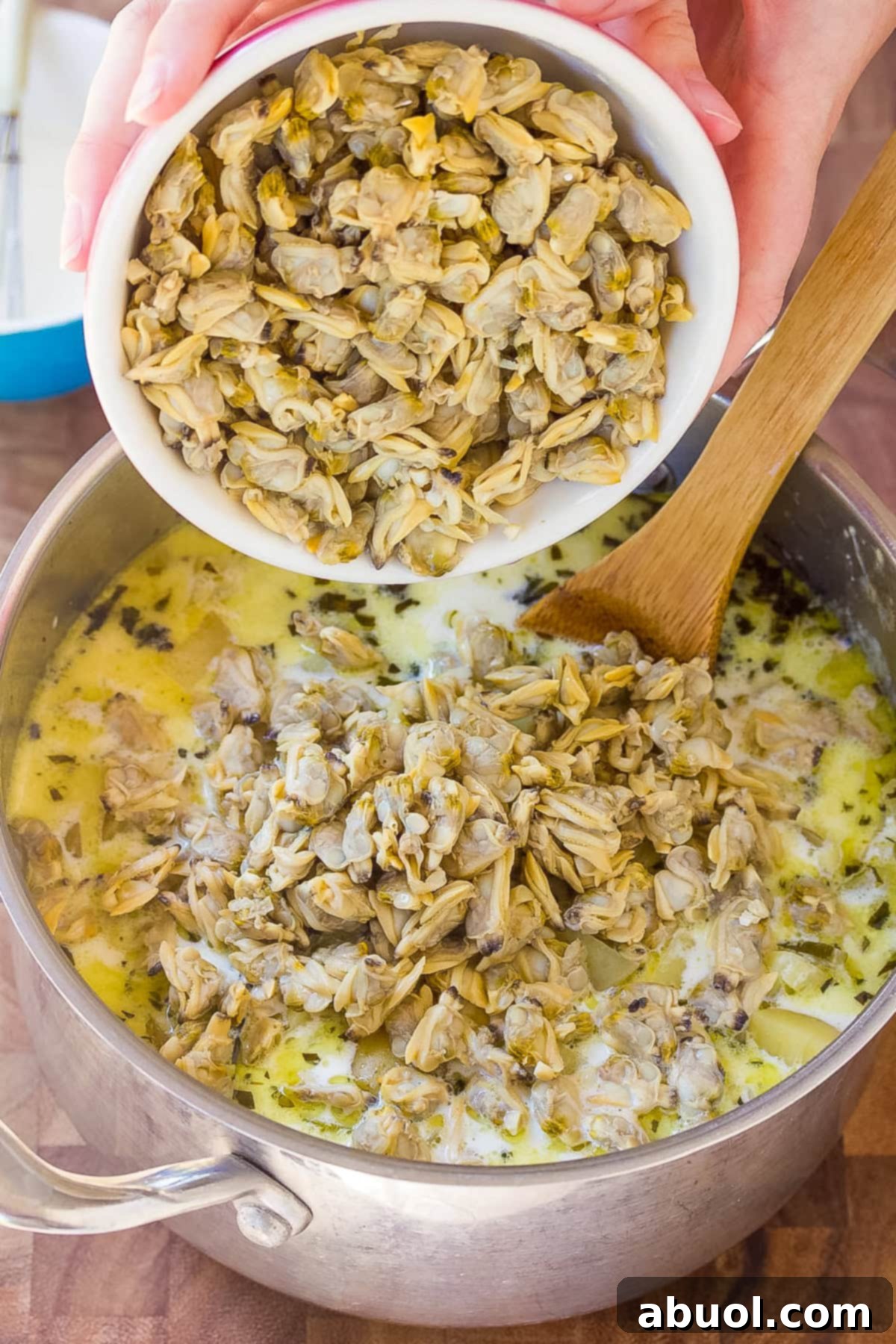 adding clams to soup pot