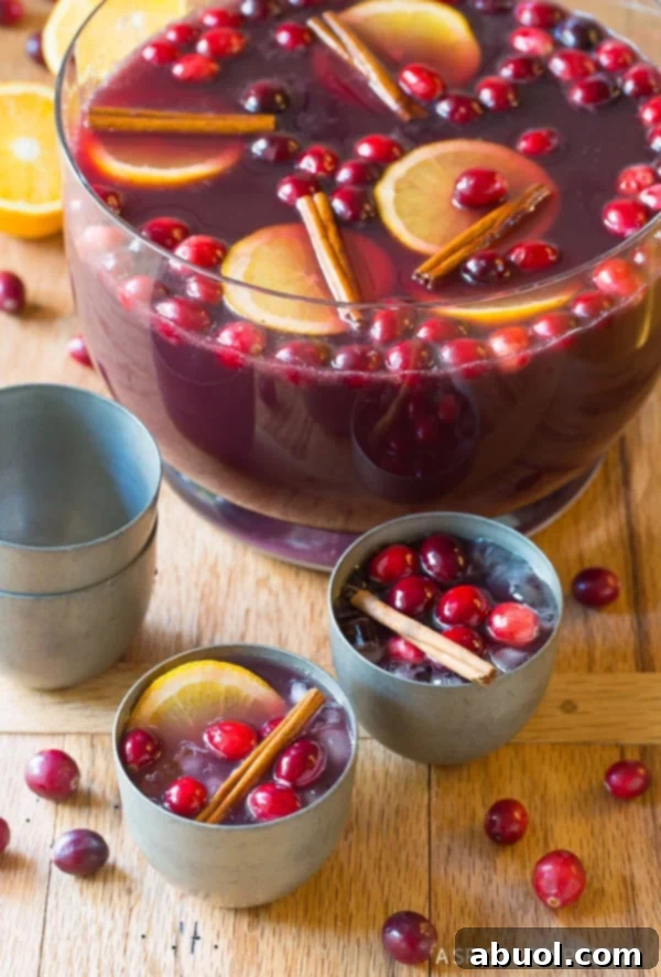 Two cups of holiday punch with more punch in a bowl in the background.