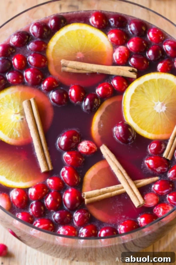 Overhead view of Wine Punch in a punch bowl with cranberries, cinnamon sticks and oranges on top.