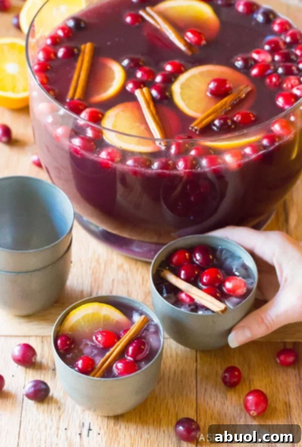 Hand grabbing a glass of wine punch recipe with the punch bowl in the background.