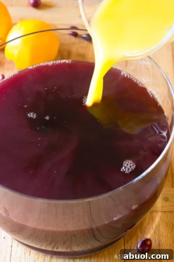 Wine Cocktails - Juice being added to the wine in the punch bowl.