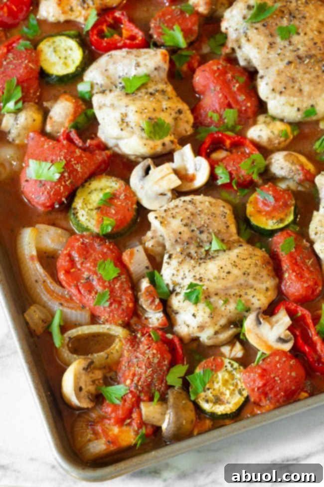 Close-up of a single piece of saucy sheet pan chicken cacciatore with rich tomato sauce