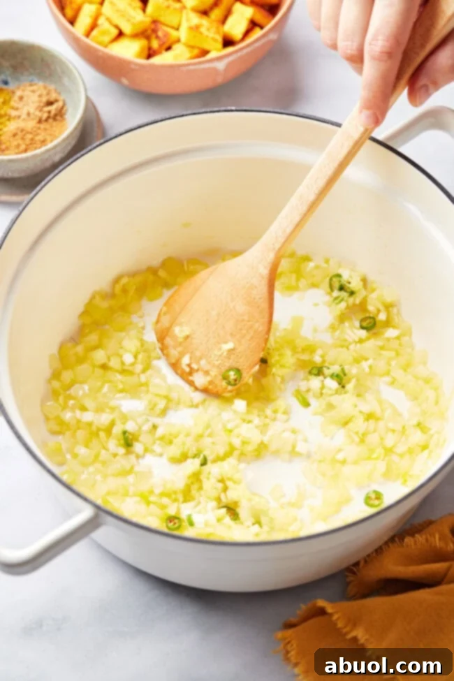 Chopped onions and spices being sautéed in a skillet, releasing their aromatic flavors.