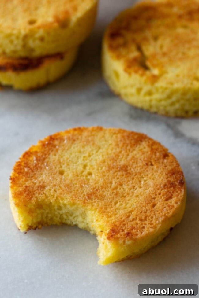 A close-up view of a perfectly textured slice of grain-free, low-carb bread, showcasing its fluffy interior and golden crust, with a clear bite taken out.
