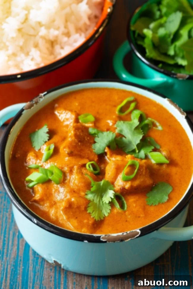 Instant Pot Butter Chicken Curry in a pot with fresh cilantro and green onion on the top, served with rice.