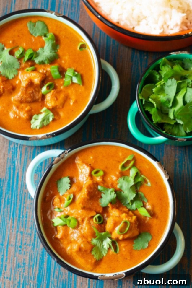 Two bowls of instant pot chicken curry next to a bowl of rice, ready to be served.