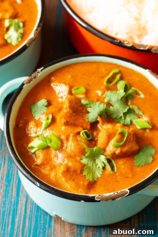 Indian Butter Chicken plated in a bowl and topped with fresh cilantro and scallions.