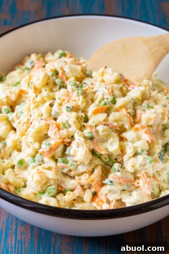 Bowl of potato and mac salad with a wooden spoon.