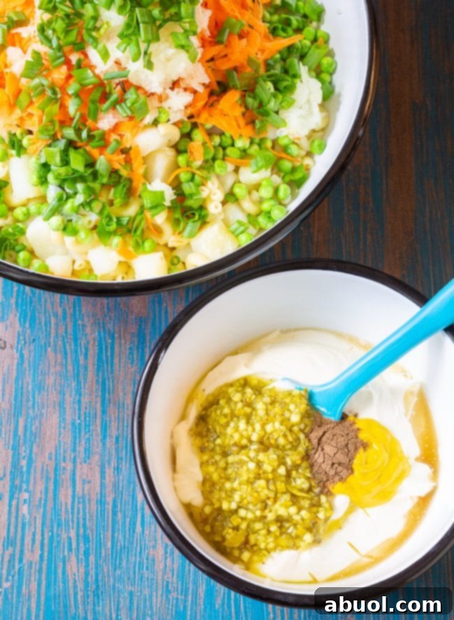 Pasta salad in one bowl with the dressing being mixing in another, smaller bowl.