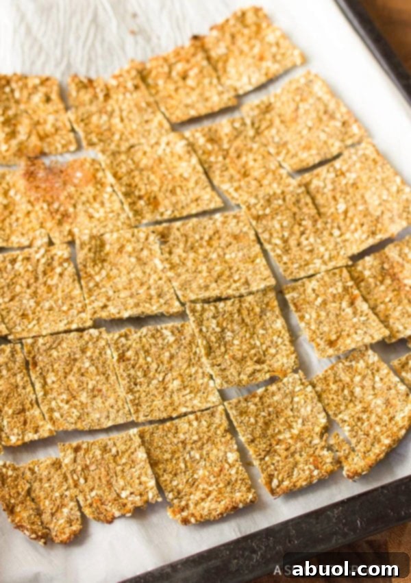 A parchment paper lined baking sheet covered with squares of grain free cauliflower crackers.