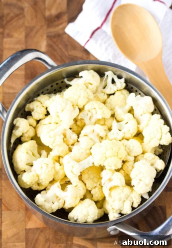 Fresh cauliflower florets in a steamer basket set in a large pot.